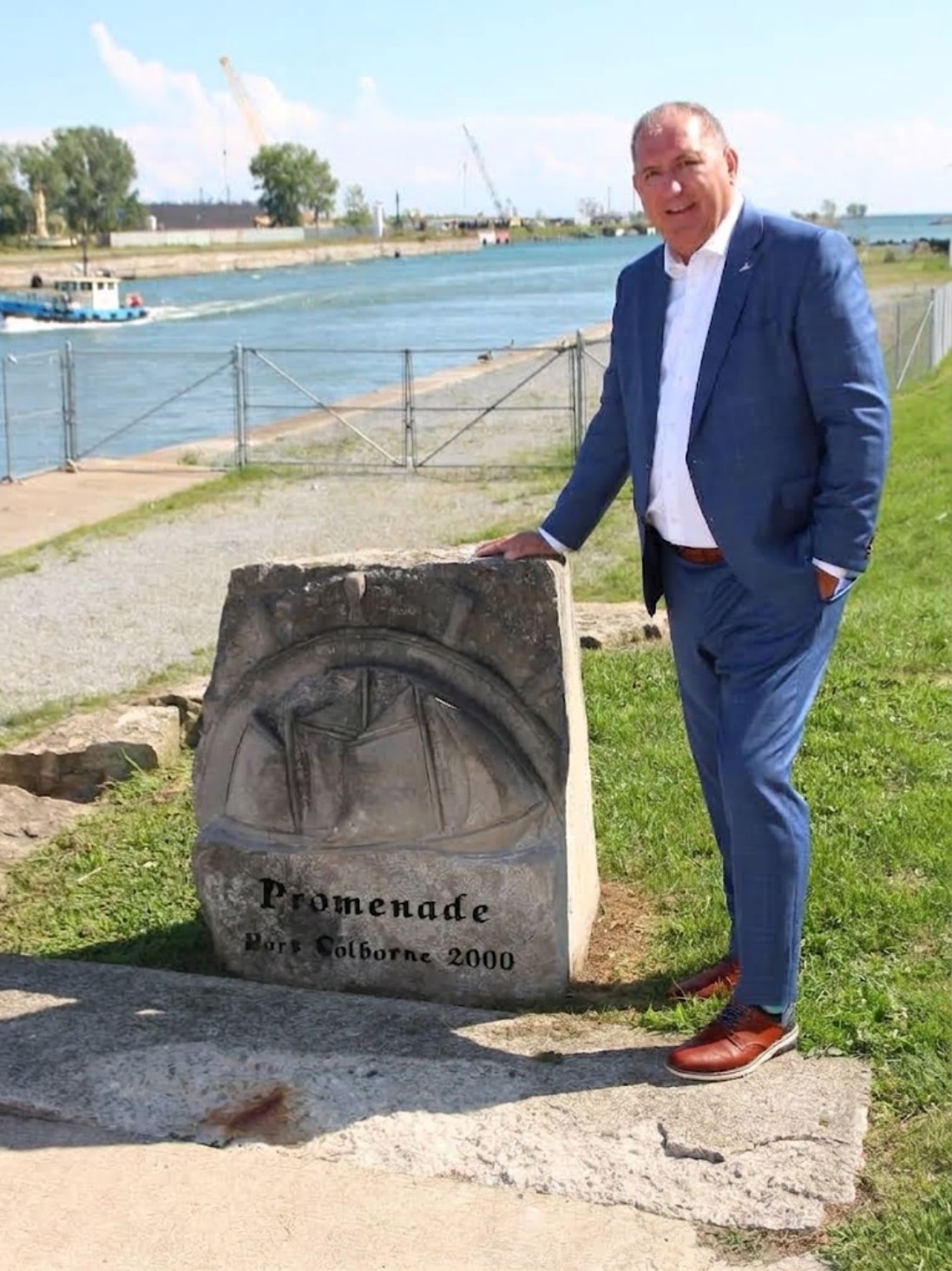 Mayor Bill Steele standing beside the Promenade Port Colborne 2000 monument on the Welland Canal